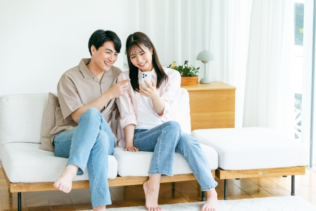 リビングでスマホを見て家事代行を依頼する夫婦